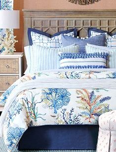 a bed with blue and white comforters in a bedroom next to a mirror on the wall