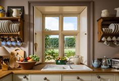 a kitchen filled with lots of counter top space next to a large open window that looks out onto a lush green field