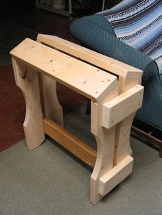 a wooden bench sitting in front of a blue chair on the floor next to a couch