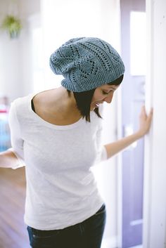 a woman wearing a blue knitted hat standing in front of a white refrigerator freezer