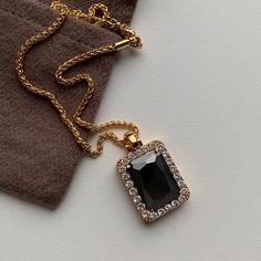 This black emerald-shaped pendant stands out from the rest. Encased by bordering crystals, this necklace is featured on our twisted gold rope chain Easily mix and match with your favorite gold pieces Material: Gold-plated Copper, Cubic Zirconia Weight: 19.1g Size: 20.8 inches with a 2 inch adjuster Elegant Black Rope Chain Necklace, Gold Rectangular Necklace For Evening, Rectangular Gold Necklace For Evening, Black Pendant Jewelry With Rope Chain, Obsidian Necklace, Gold Rope Chains, Gold Piece, Black Stone, Rope Chain