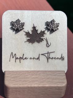 the maple and threads logo is engraved on a wooden card holder with two leaves