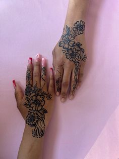 two hands with henna tattoos on them, one holding the other's hand