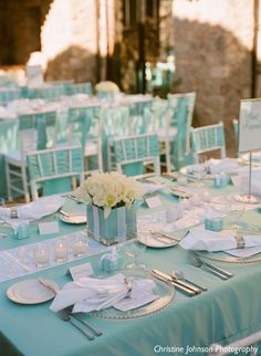 the table is set with white flowers and place settings for an elegant dinner or reception