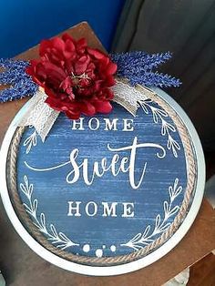 a sign that says home sweet home with a red flower on the front and blue background