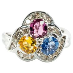 This gorgeous estate ring is finely crafted in solid 14K White Gold and set with genuine Earth mined Sapphires: blue, pink, and yellow gems. Each oval cut stone measures 5mm x 4mm totaling 1.35 carats. These amazing gems are so clean, clear, and transparent, with great intensity and strong brilliance. 18 surrounding diamonds are SI1 clarity and I color totaling .45 carat. Plus one .02 carat single cut diamond of VS1 clarity and G color in the middle. The top of the ring measures 13mm top to bott Estate Ring, Yellow Gems, Estate Rings, Sapphire Diamond Ring, Pink Ring, Pink And Yellow, Three Stone Rings, Yellow Sapphire, Pink Diamond