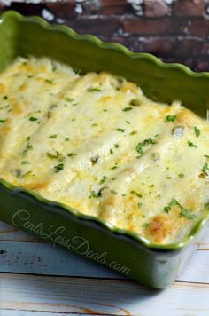 a green casserole dish with cheese and herbs in it on a wooden table