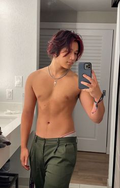 a shirtless young man taking a selfie in the mirror with his cell phone