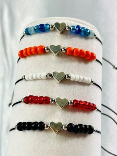 four bracelets with heart charms on them sitting on top of a white cloth roll