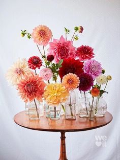 a wooden table topped with lots of vases filled with flowers on top of it