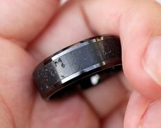 a close up of a person holding a wedding ring in their hand and wearing it