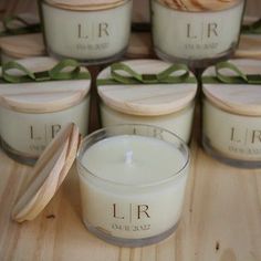 several candles are sitting on a wooden table with green ribbon around them and one candle is in front of the others