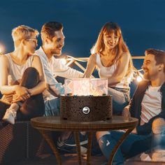 a group of people sitting around a table with a cake in the shape of a fire