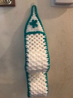 a green and white crocheted towel hanging on the wall next to a light switch