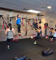 a group of people in a gym doing exercises with resistance straps on the wall behind them