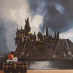 a painting of hogwart's castle on the wall in front of a suitcase