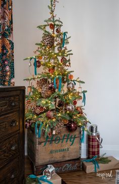 a small christmas tree with pine cones and ornaments in a wooden crate on the floor