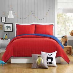 a bed with red bedspread and pillows in a child's bedroom