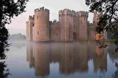 a castle sitting on top of a lake surrounded by trees