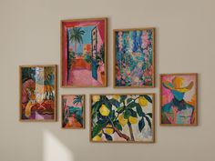 six paintings hang on the wall above a bed