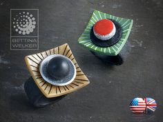 two rings with designs on them sitting on a table next to an american flag pin