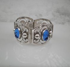 "Up for sale is this beautiful carved blue sapphire glass 925 sterling silver panel bracelet made in Mexico. It features 4 carved glass mask heads and four 1.5\" wide by 1.25\" high sterling silver hinged panels. The length is 7\" long, but fit 6.5\". the bracelet weighs 34.99 grams. On the box clasp it is marked \"Hecho En Mexico DF\" in a circle and in the middle it have \"0925 TNC\". This is in beautiful condition and would make a great gift. Please review all images carefully as they are als Blue Sterling Silver Engraved Bracelet, Blue Engraved Sterling Silver Bracelets, Elegant Blue Sterling Silver Bracelet Stamped 925, Unique Engraved Blue Bracelets, Elegant Blue Sterling Silver Bracelet, Unique Blue Etched Jewelry, Unique Etched Blue Jewelry, Blue Oval Carved Jewelry, Blue Vintage Sterling Silver Bracelet