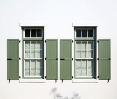 two windows with green shutters on each side