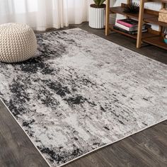 a white and black area rug in a living room with wood flooring on the side