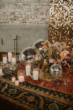 a table with candles and flowers on it in front of a mirror ball wallpaper