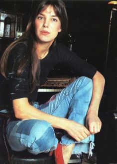 a woman sitting on top of a stool next to a keyboard