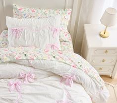 a white bed with pink bows on the pillows and pillowcases in a bedroom