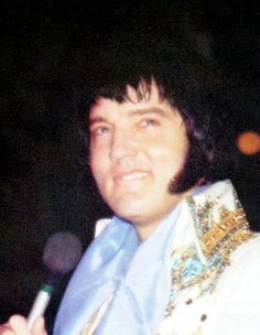 a man in elvis clothing holding a microphone