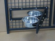 two metal bowls sitting on top of each other in front of a wall mounted dog feeder