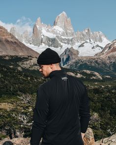 a man standing on top of a mountain looking at the mountains in front of him