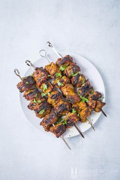 several skewers of food on a white plate