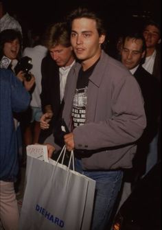 a man holding a shopping bag in front of a group of people at an event