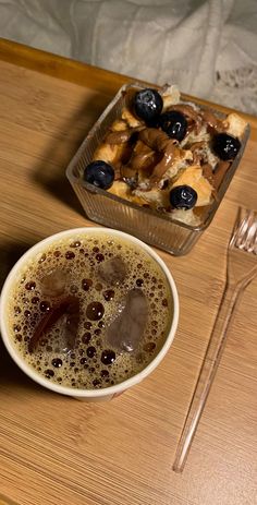 a cup of coffee next to a tray of food on top of a wooden table