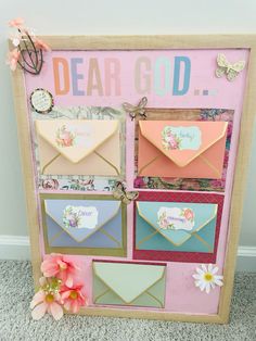 a pink and blue sign that says dear god with envelopes on it next to flowers