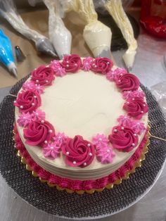 a cake with pink frosting and flowers on it sitting on a table next to other items