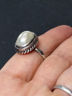 ► ABOUT THIS RING This is a vintage sterling silver statement ring with 1 off-white imitation Pearl. Wonderful craftsmanship. The front of the ring is 18x14mm. The ring band is 2.5mm wide. Our family acquired this ring around 1996, as part of a large jewelry collection. It's in great condition, unworn, antiqued and may be tarnished. It's been in storage all of these years. This ring would make a nice addition to any collection of beautiful heirloom jewelry. ► MORE FROM THIS SHOP See our other pe Elegant White Crystal Ring Stamped 925, White Open Ring Stamped 925, White Stamped 925 Open Ring, Vintage Pearl Ring With Gemstone, Classic White Cabochon Moonstone Ring, Classic Adjustable Oval Pearl Ring, Classic Silver Cabochon Pearl Ring, White Nickel-free Rings For Anniversary, Elegant Nickel-free White Rings