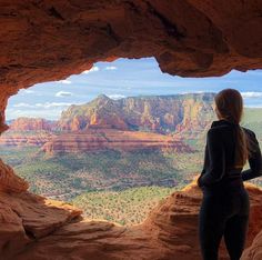 a woman standing on top of a cliff looking out at the mountains and canyons