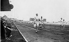 the men are running on the track in an old time race photo, with spectators watching