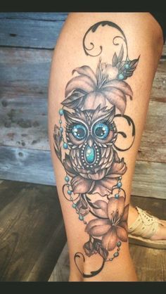 a woman's leg with an owl and flowers tattoo on it