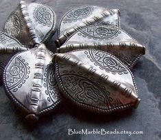 four pieces of metal sitting on top of a black stone surface, with intricate designs in the middle