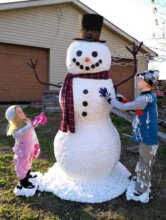 two children are building a snowman in the yard