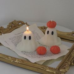 two candles with fake ghost faces on them sitting in front of a mirror and paper