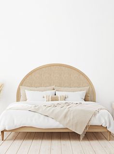 a bed with white linens and pillows in a room that has wood flooring