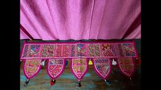 an elaborately decorated pink cloth hanging from a wall