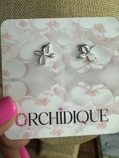 a pair of earrings is shown in front of a card with the word orchidique on it