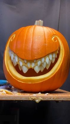 a carved pumpkin with teeth and fangs on it's face, sitting on a table